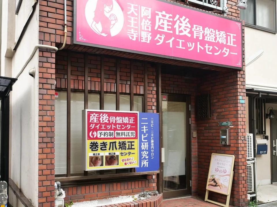 赤茶色のレンガの建物。入口の右側にゆのゆの看板があります