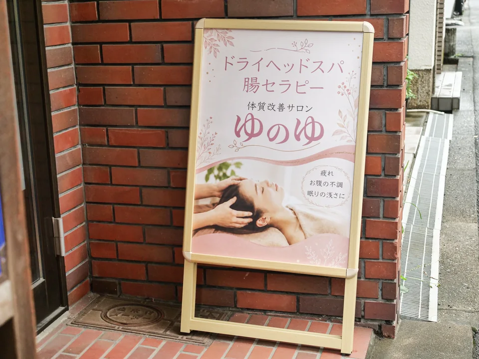 入口のレンガの壁の前に置かれた、ピンク色のゆのゆの看板